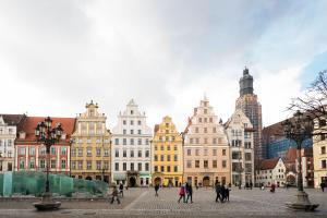 a group of people walking around a city with buildings at Rynek 2B - Old Town in Wrocław