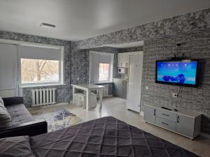 a living room with a television on a brick wall at Сдаётся однокомнатная квартира Люкс возле озера. in Balqash