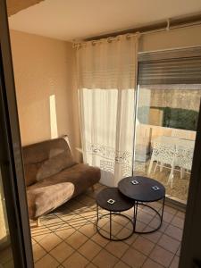 a living room with a couch and two tables in front of a window at L'Enclos de la plage in La Ciotat +23 photos