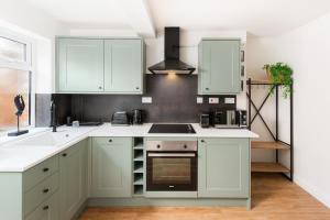 a kitchen with white cabinets and a stove top oven at Stylish 2-Bedroom Townhouse in Stratford upon Avon in Stratford-upon-Avon