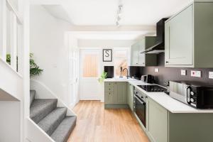 a kitchen with white cabinets and a stairway at Stylish 2-Bedroom Townhouse in Stratford upon Avon in Stratford-upon-Avon