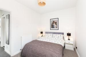 a white bedroom with a bed and two night stands at Stylish 2-Bedroom Townhouse in Stratford upon Avon in Stratford-upon-Avon