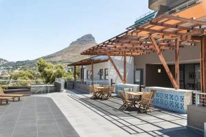 a patio with tables and chairs with a mountain in the background at Central Apartment in Cape Town in Cape Town