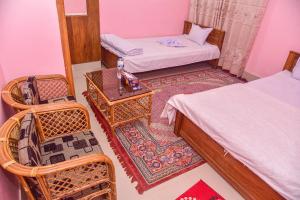 a room with two beds and a table and chairs at Al Hera Resort in Sreemangal +9 photos