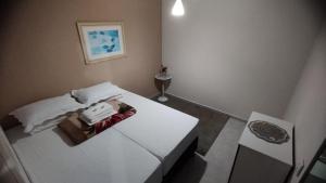 a small bedroom with a white bed and a table at KITNET DU VÔ - Cantinho Du Vô in Santa Teresa