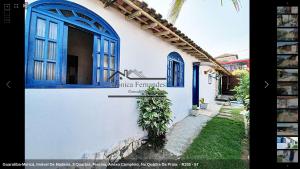 a white building with blue windows and a plant at 50 metros da praia in Maricá