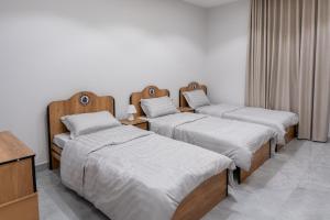 three beds in a room with white walls at The view apartment 1 in Al Baha