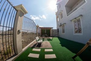 a patio with green grass and a fence at The view apartment 1 in Al Baha