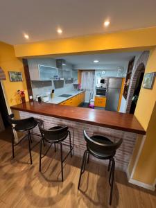 a kitchen with a large wooden bar with four chairs at Garelly 2 in San Vicente de la Barquera