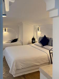 a bedroom with two beds with white sheets and blue pillows at Hotel Al Alba Hammam & Restaurant in Asilah