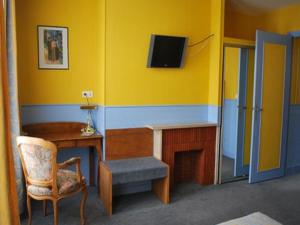 a room with a desk and a chair and a tv at Logis Le Normandie in Caudebec-en-Caux