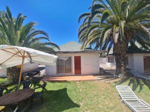 a house with palm trees and a table and an umbrella at Cabañas Yunkai in Vicuña