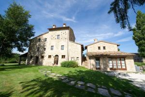 un antiguo edificio de piedra con una torre en un campo de césped en Agriturismo Verziere, en Fermignano