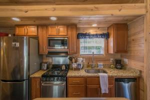 a kitchen with wooden cabinets and a stainless steel refrigerator at Lakeview 2BR Tiny Home near Trails and Bocce in Flat Rock +28 photos