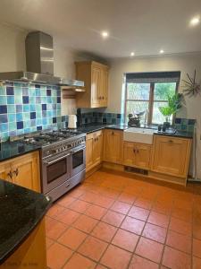 a kitchen with wooden cabinets and a stove top oven at Spacious Village House near Oxford with Woodburner in Horspath