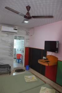 ein Wohnzimmer mit einem Deckenventilator und einem TV in der Unterkunft hotel prashant international in Gandhidham