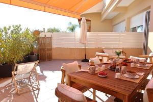 a patio with a wooden table and chairs at Bel appartement avec piscine en bord de mer in Ajaccio