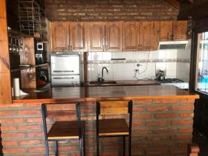 a kitchen with wooden cabinets and a brick wall at el cabure casa de campo in Esquel