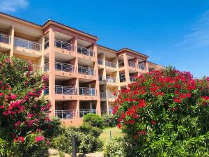 un immeuble d'appartements avec des fleurs rouges devant dans l'établissement Très bel appartement avec piscine en bord de mer, à Ajaccio