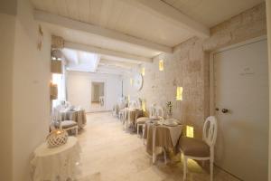 a restaurant with white tables and chairs and a room at Playa del Mar - Adults Only in Monopoli