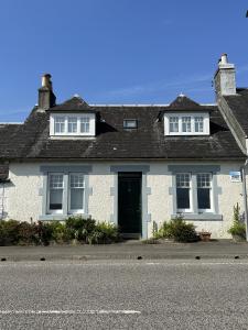 a white house with a black door on a street at Traditional Inveraray Cottage - Amazing Loch Views in Inveraray