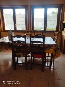 a dining room table with two chairs and two windows at 3 Chambres chez l'habitant in Valleiry