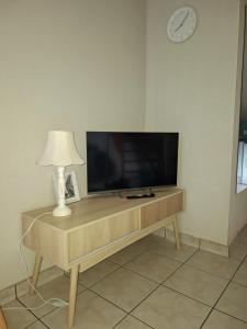 a flat screen tv on a wooden table with a lamp at L'étape du Theil in Le Theil-de-Bretagne