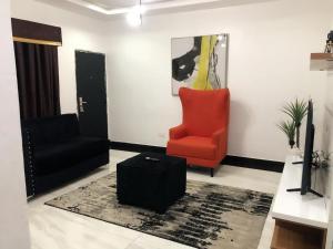 a living room with a black chair and a red chair at Auxano Apartments in Abuja