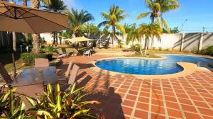 a swimming pool in a yard with palm trees at Lujosa casa vacacional con piscina privada in Playa Guacuco