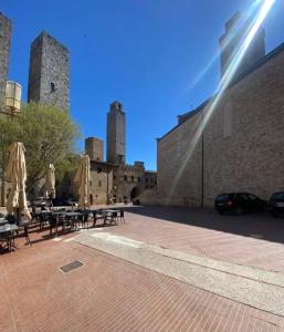 a patio with tables and umbrellas in front of a building at Appartamento Le Rondini in San Gimignano