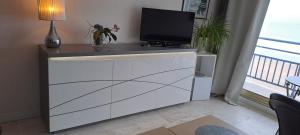 een witte ladekast met daarop een televisie bij STUDIO MEUBLE Face mer vue imprenable sur la mer, parking et fibre gratuits in Les Sables-dʼOlonne +17 foto's