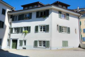 a white building with green shuttered windows at Loft in the historical center - Symbol 4 in Zürich