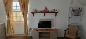 a room with a television on a table with a chair at The Studio Trewarveneth Manor Farm TR185NF in Newlyn