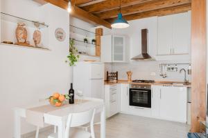 a kitchen with white cabinets and a white table and chairs at Casa Velella in Castellammare del Golfo