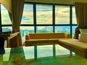 Una sala de estar con un sofá y una ventana grande. en Spacious 2BR Stay 5 Queen Beds for Large Groups, en Jelutong