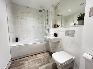 a white bathroom with a sink and a tub and a toilet at Luxury 11th-Floor Penthouse - 2 Bed 1 Bath - City Centre Views - Gym & Netflix in Birmingham