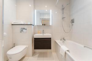 a white bathroom with a tub and a sink and a toilet at Chesham Court Knightsbridge in London +60 photos