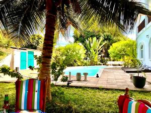 a pool with two chairs and a palm tree at Hibiscus WhiteHouse in Brufut +9 photos