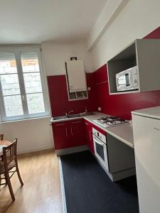 eine Küche mit roten Schränken und einem Herd mit Backofen in der Unterkunft Appartment Doutre-2e étage in Angers