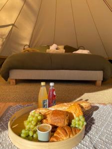 a plate of bread and grapes on a table in a tent at Tente luxe avec jacuzzi vue lac 3 in Le Vigeant