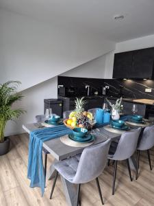 a dining room with a table and chairs with fruit on it at Luxsuite Still und Komfort 2 Balkon Elektrogrill Tischfussball TV-75 Zoll in Dinslaken