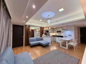 a living room with a blue couch and a kitchen at Modern 1BR Unit in Abreeza Place T2 with Pay Parking in Davao City