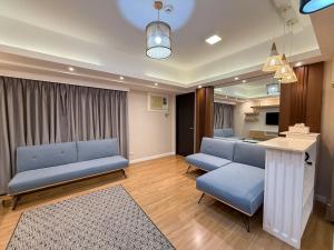a living room with blue couches and a table at Modern 1BR Unit in Abreeza Place T2 with Pay Parking in Davao City