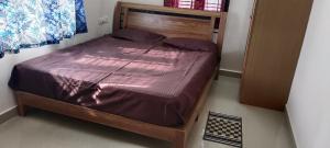 a bed with a wooden frame in a room at "Ambi's stay " A unique and Secluded Nest with serene calmness views on a Traffic-Free Street at Bommasandra 3 km from Narayana Hrudayalaya Hospital in Bangalore