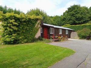 ein Haus mit einer roten Tür und einem grünen Hof in der Unterkunft Strathpeffer Holiday Cottages in Strathpeffer