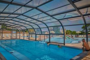 a swimming pool with a retractable roof at Camping Le Chêne Gris in Pommeuse