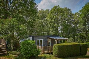a tiny house in a yard with trees at Camping Le Chêne Gris in Pommeuse