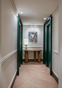 a hallway with green doors and a table with a lamp at Vincci Soho in Madrid