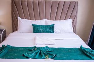 a bed with green and white sheets and pillows at The Monarch Suites- Peaceful Luxe 2BR with view in Nakuru