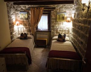 a bedroom with two beds in a stone room at Arcera AGRITURISMO in Piana di Forcella